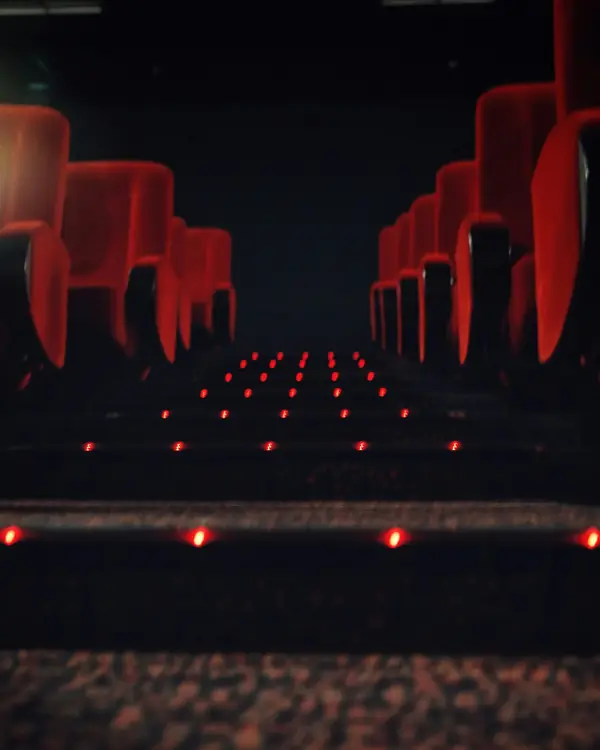 Red cinema seats and small aisle lights glowing in a dark auditorium