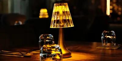 A glowing table lamp and water glasses on a wooden table in a dimly lit dining room (example photo, not of this place)
