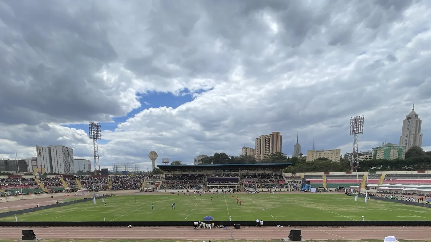 Nyayo National Stadium in Nairobi on a match day, the main stand and the city skyline under a big cloudy sky