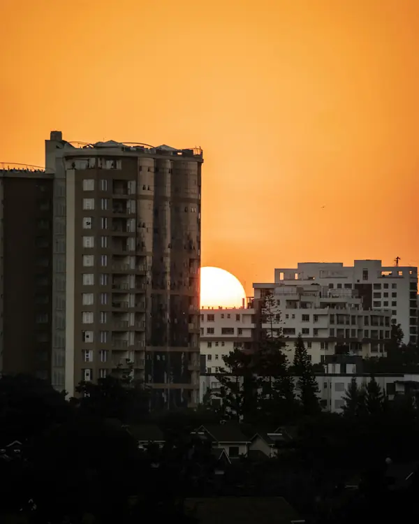 The sun setting between apartment buildings against an orange sky